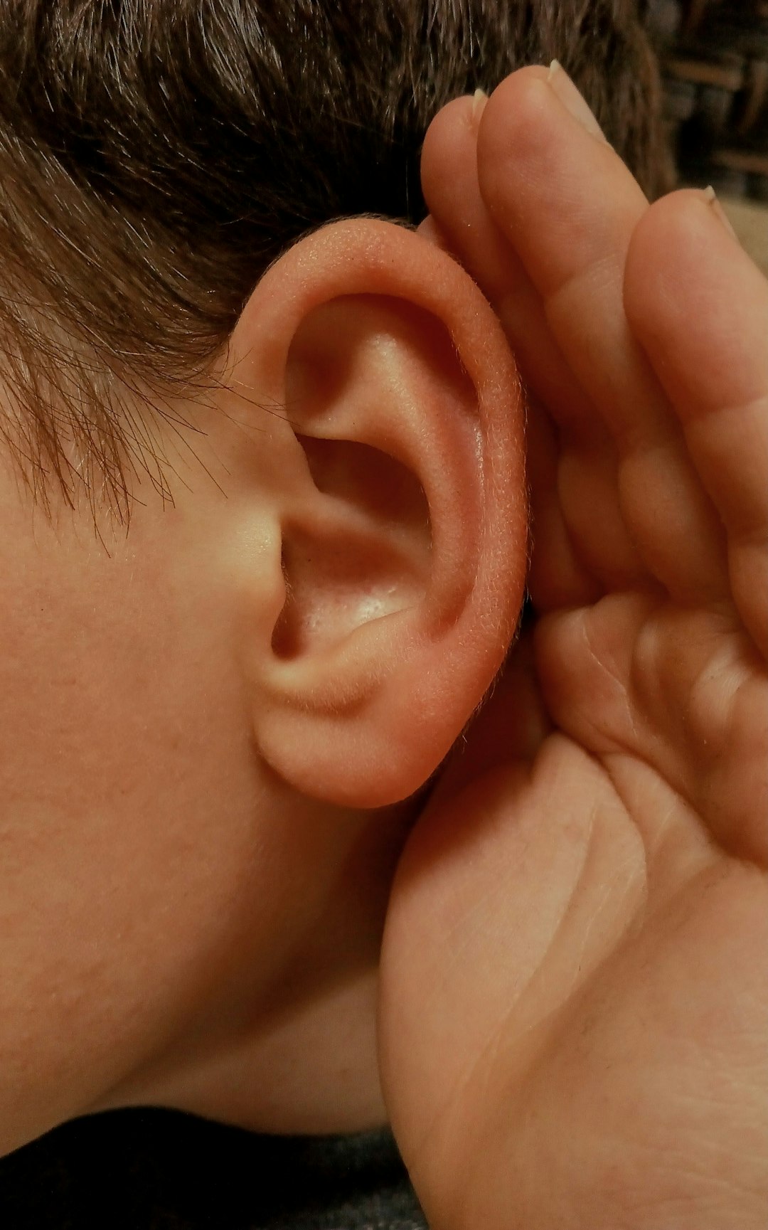 Person cupping ear representing hearing health support