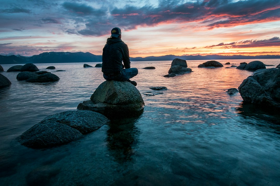 Person sitting calmly by water representing mental clarity